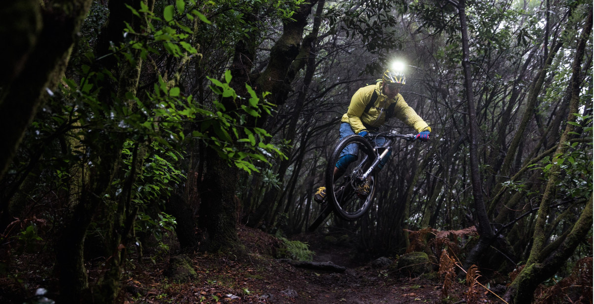 Tay lái điều khiển xe đạp MTB trong điều kiện trời tối ẩm ướt