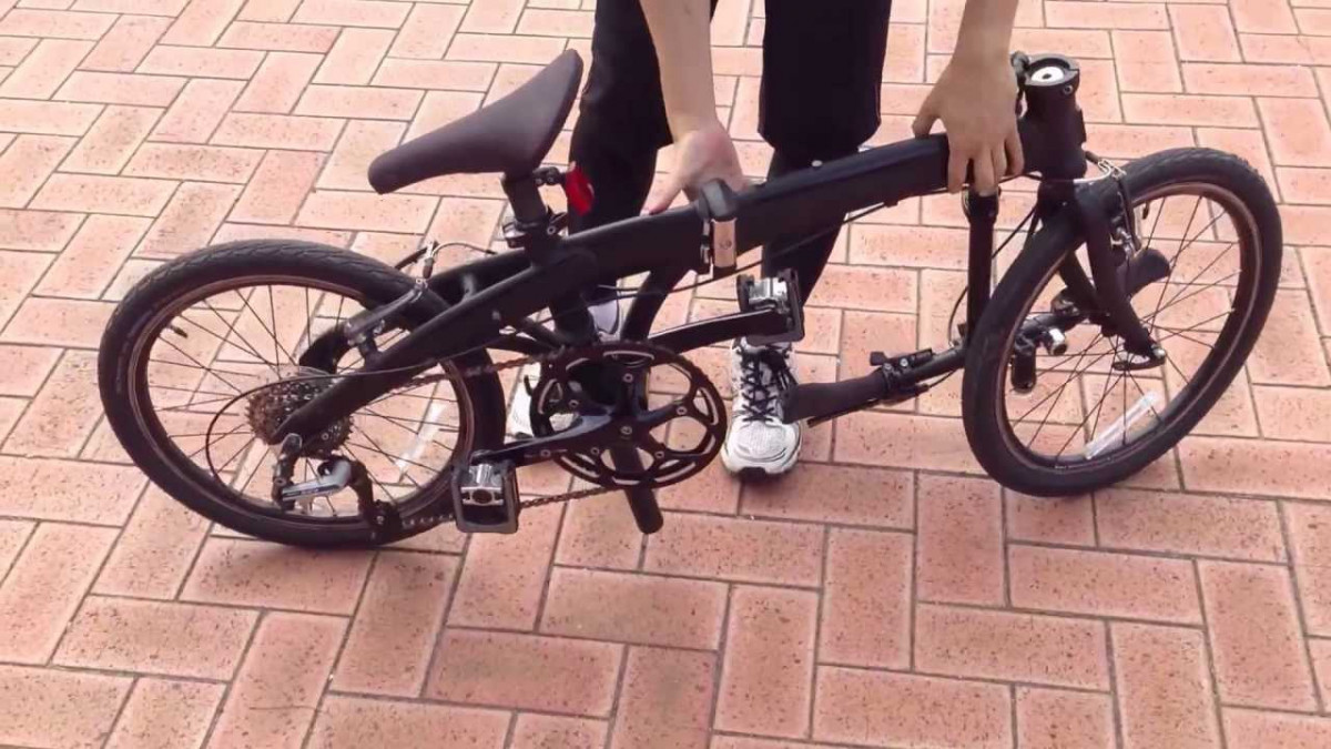 Một người đang thực hiện thao tác làm gọn xe đạp gấp